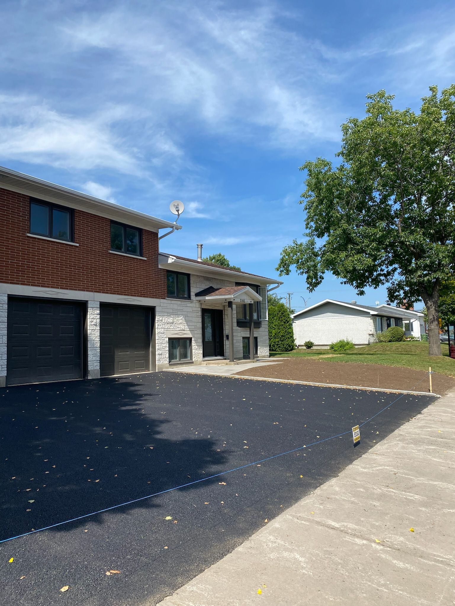 Une maison avec une allée et un trottoir devant.