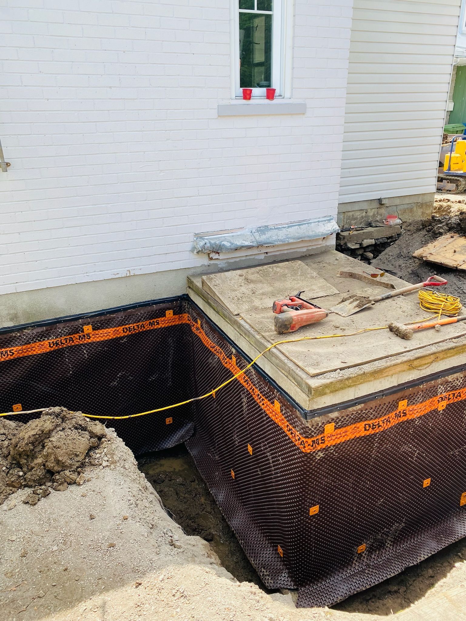 Un grand trou dans le sol devant un bâtiment en briques blanches.