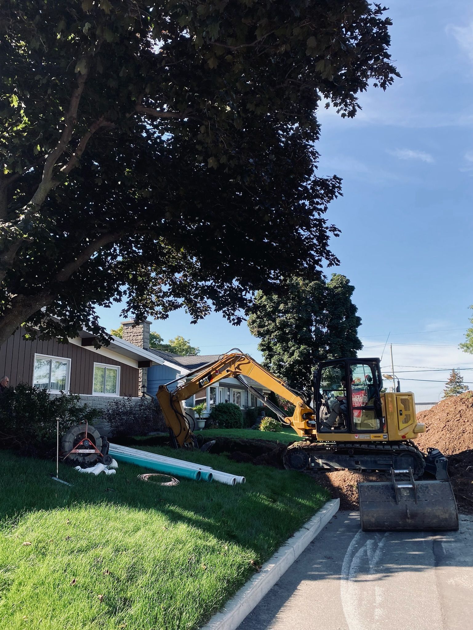 Une excavatrice jaune creuse un trou dans le sol devant une maison.