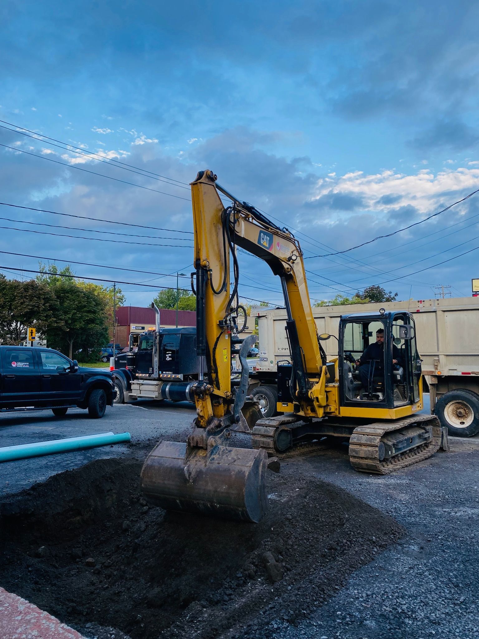 Une excavatrice jaune creuse un trou dans un terrain de gravier.