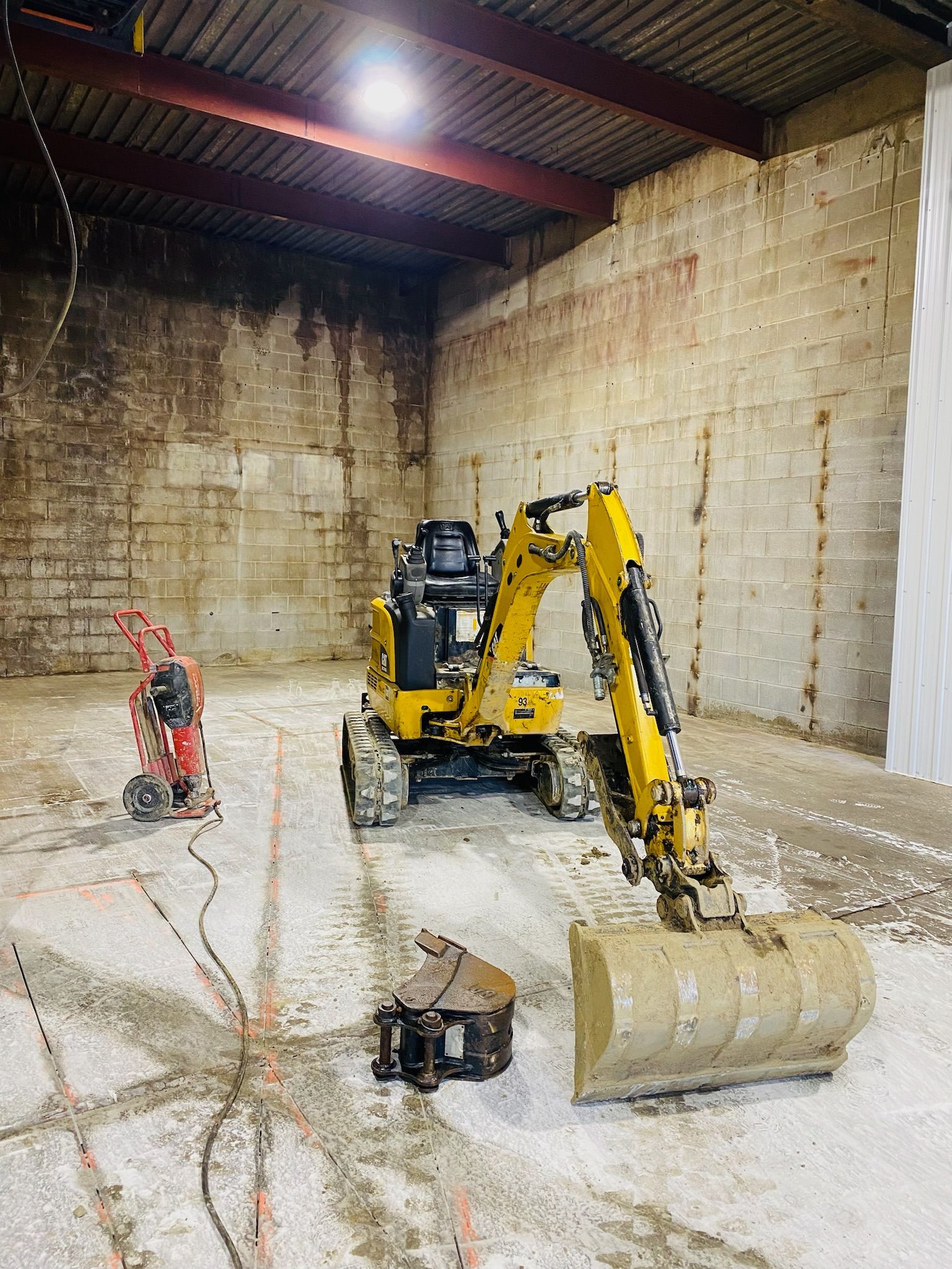Une excavatrice jaune est assise dans un grand entrepôt.