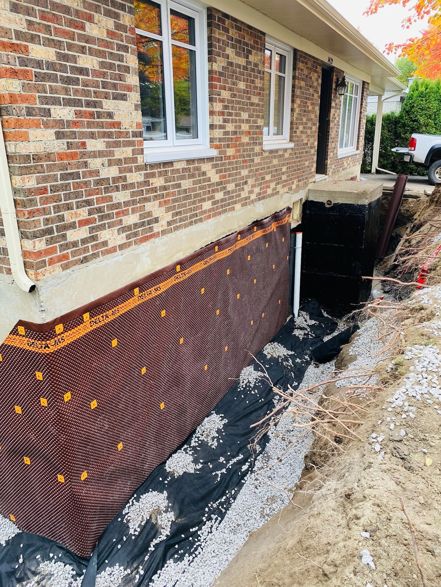 Une maison en brique avec un système de drainage installé sur le côté.