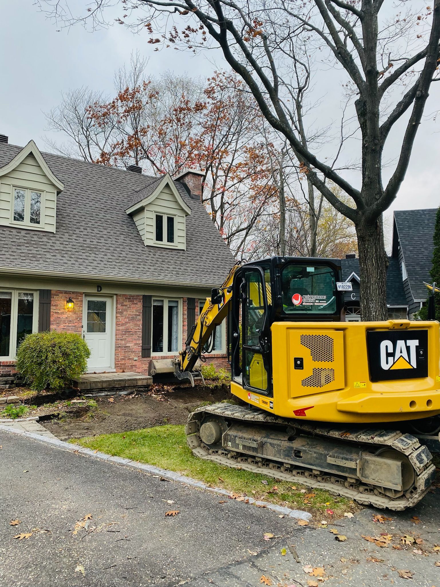 Une excavatrice jaune est garée devant une maison.