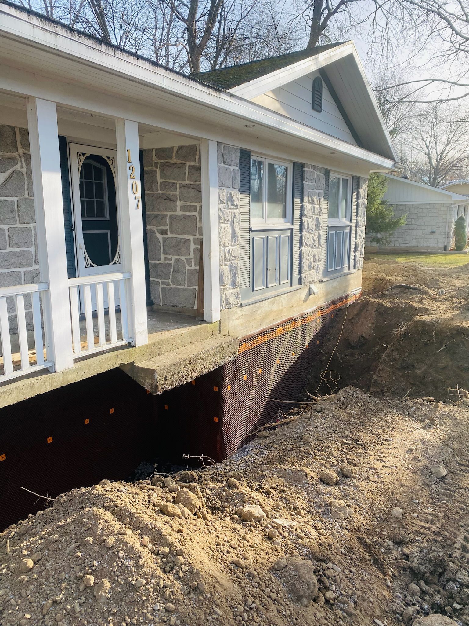 Une maison avec un porche et des fondations en construction.