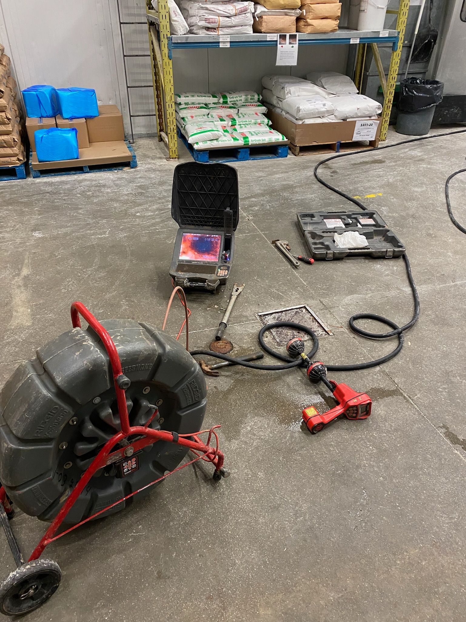 Un entrepôt avec un serpent de drainage et une perceuse sur le sol.