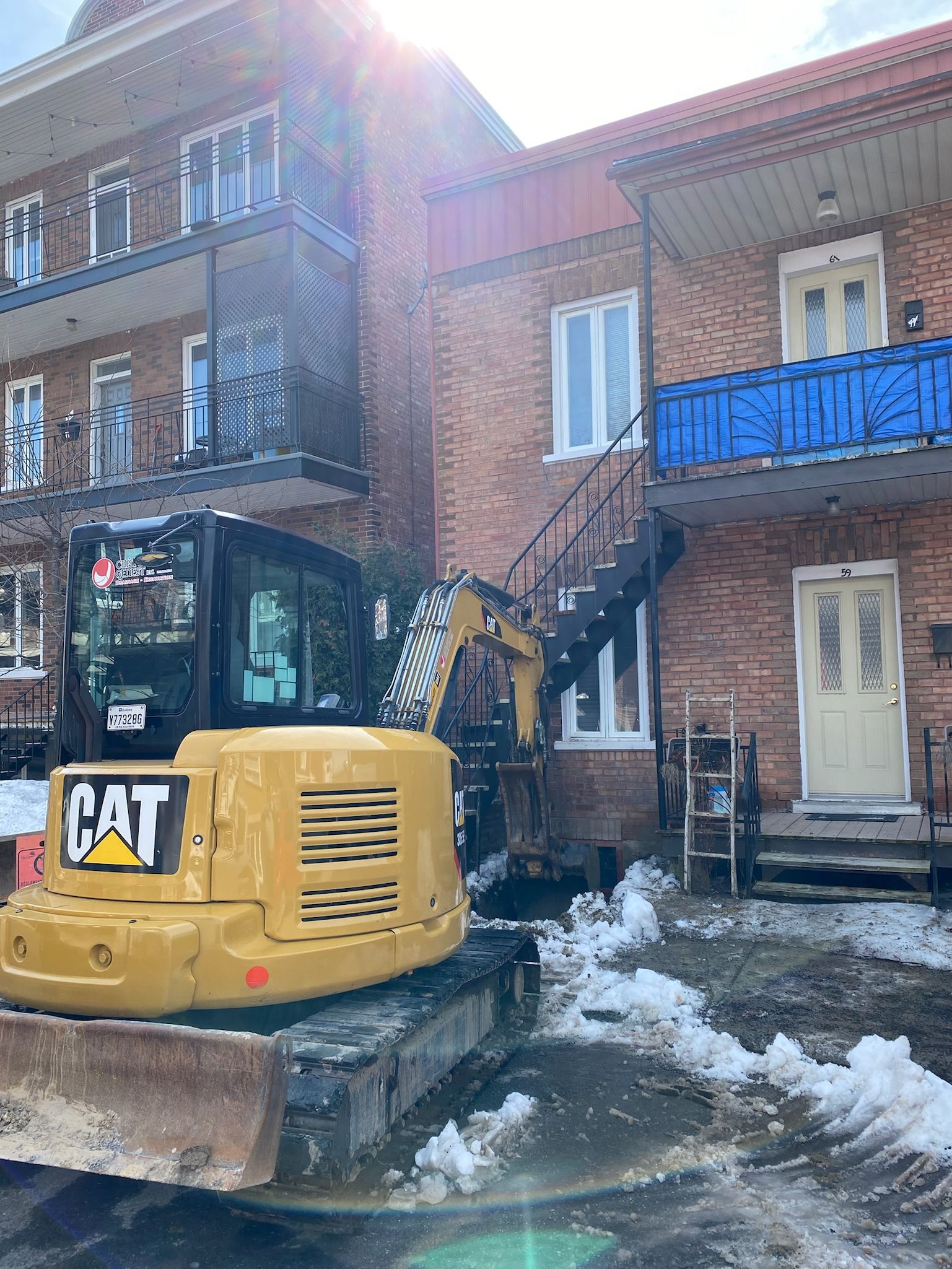 Une excavatrice à chat est garée devant un bâtiment en briques.