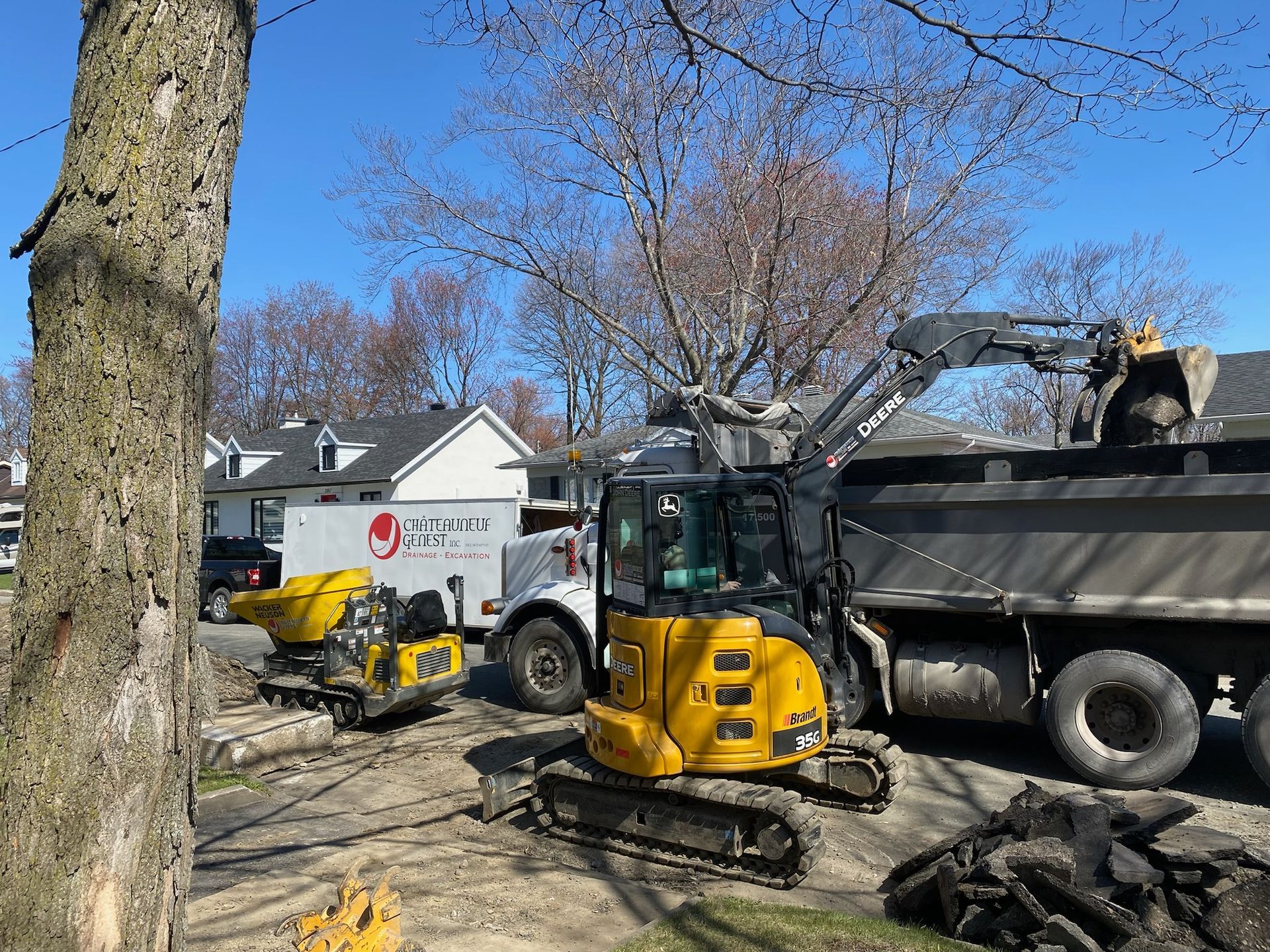 Une excavatrice jaune charge de la terre dans un camion à benne basculante.