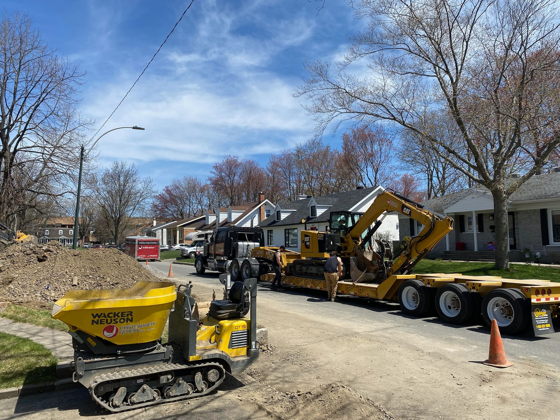 Un camion à benne basculante est garé sur le bord de la route à côté d'un véhicule de construction.