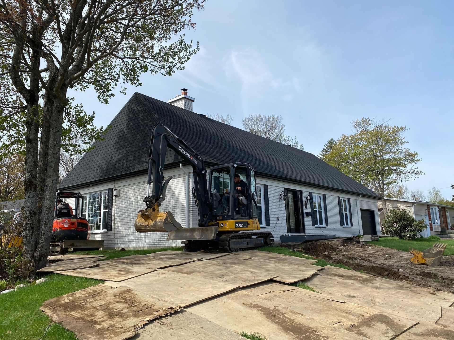Une maison est en train d'être démolie avec un bulldozer devant elle.