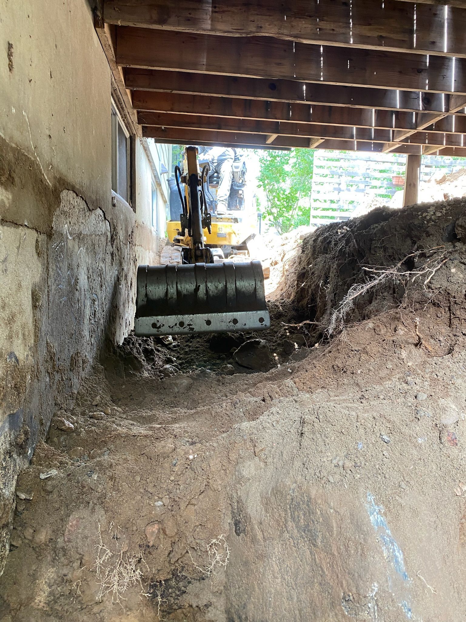 Un bulldozer creuse un trou sous une maison.