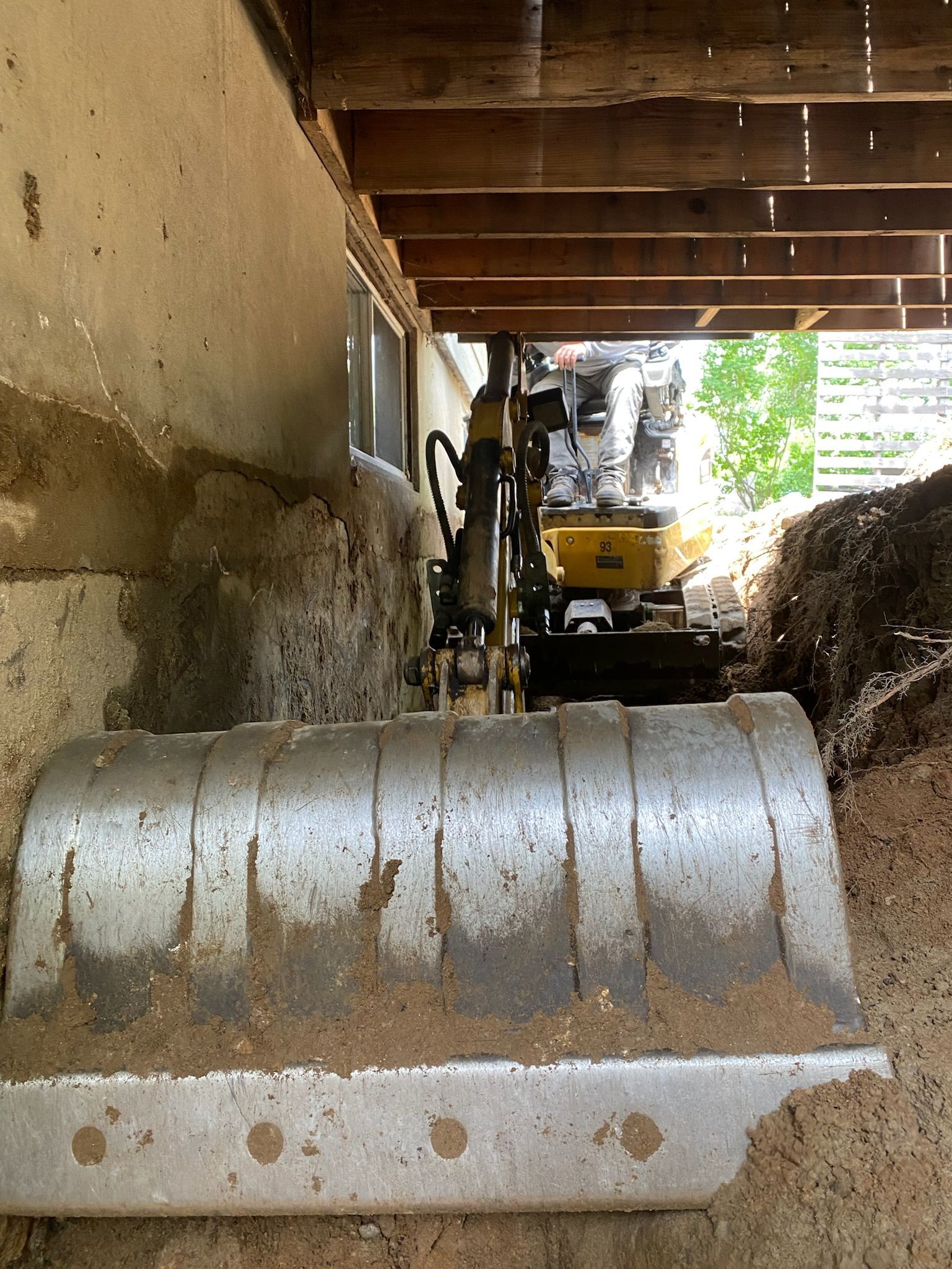Un bulldozer creuse un trou sous une maison.