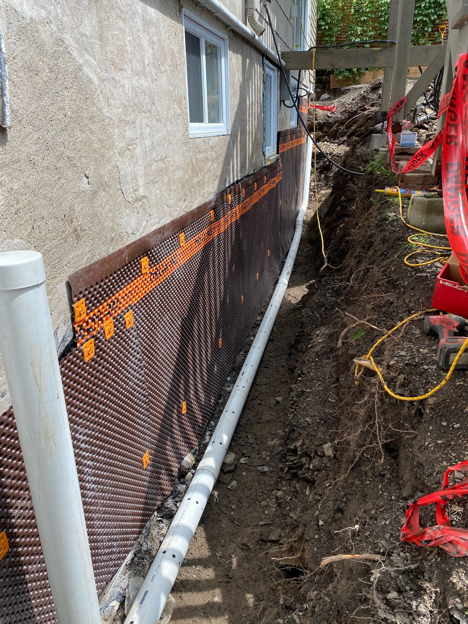 Un système de drainage est en cours d'installation sur le côté d'une maison.