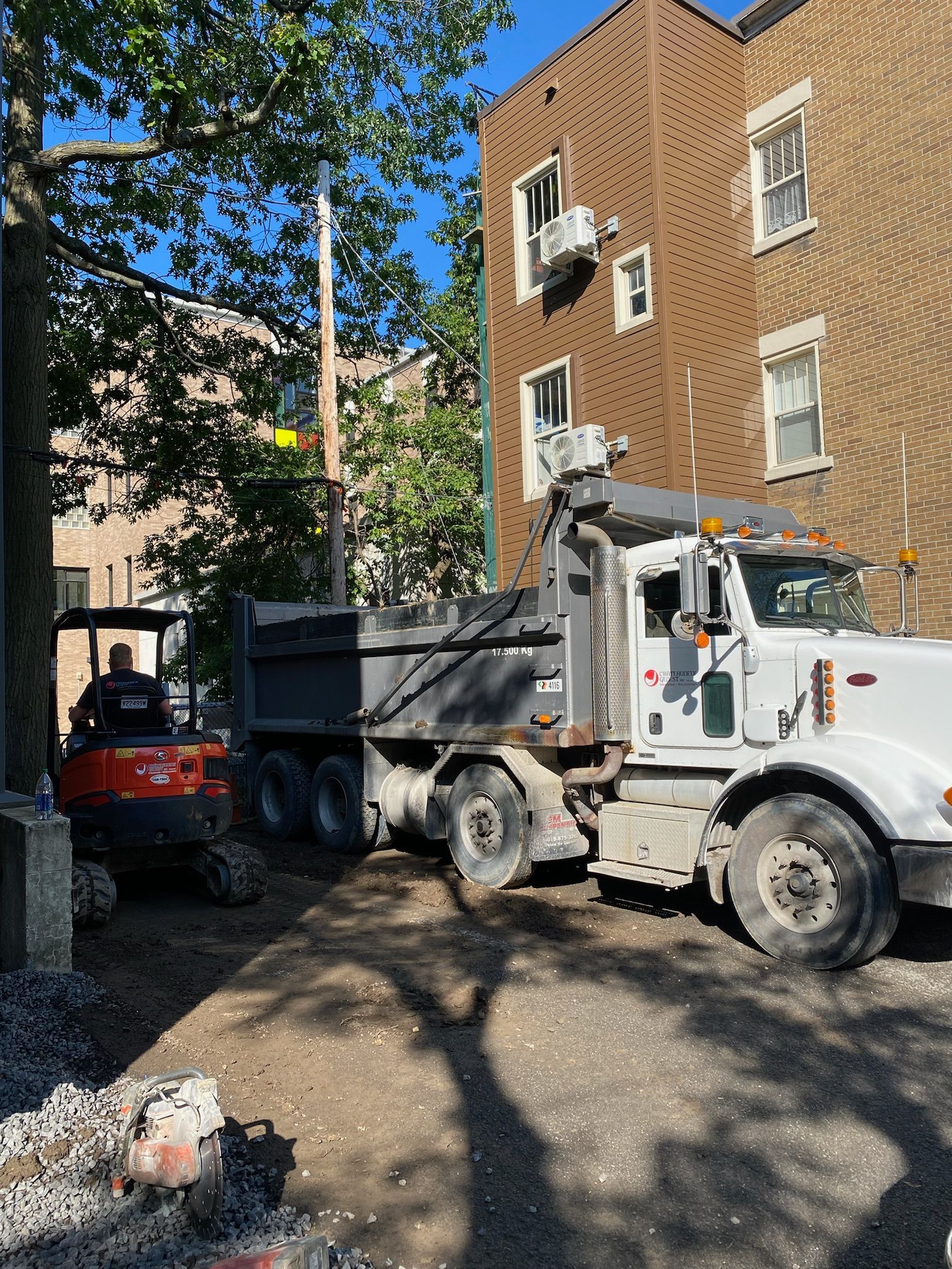 Un camion à benne basculante est garé devant un bâtiment en briques.