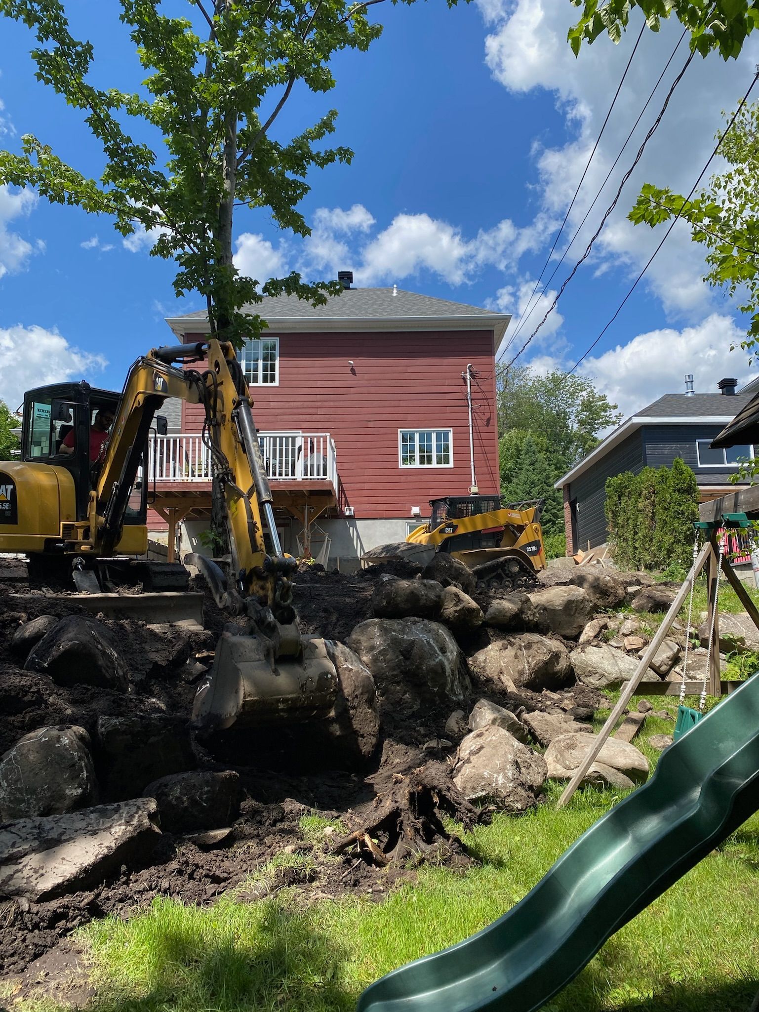 Un chantier avec un toboggan et une maison en arrière-plan.