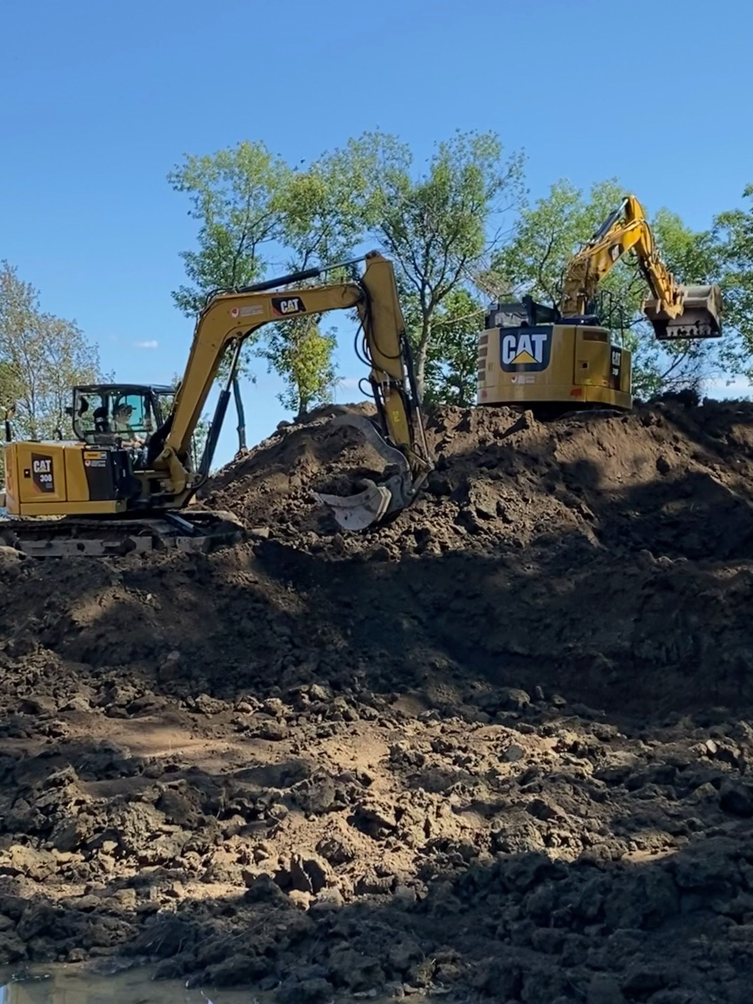 Deux excavatrices Cat travaillent sur un tas de terre.