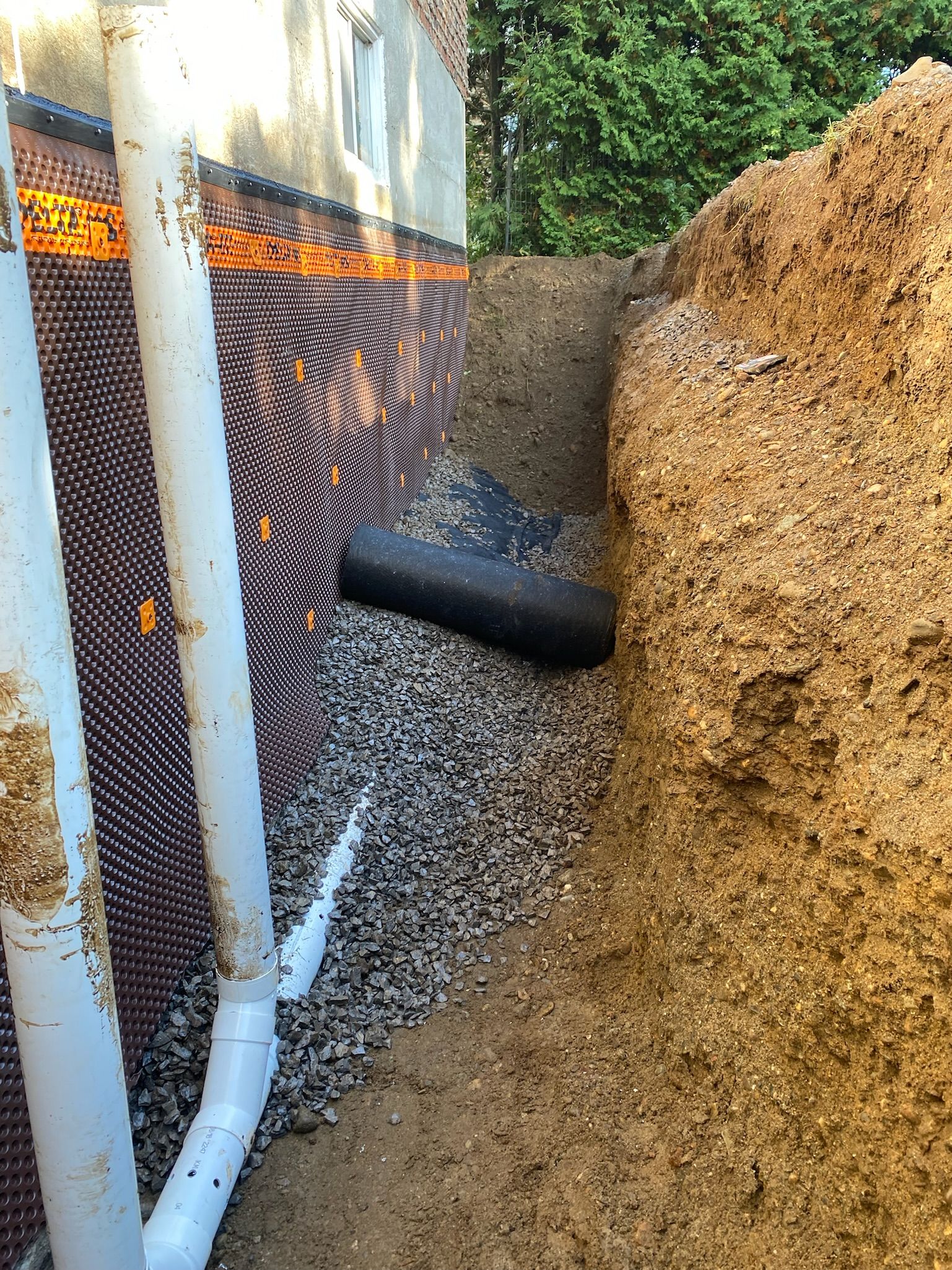 Un tuyau est en train d'être installé dans la terre à côté d'une maison.