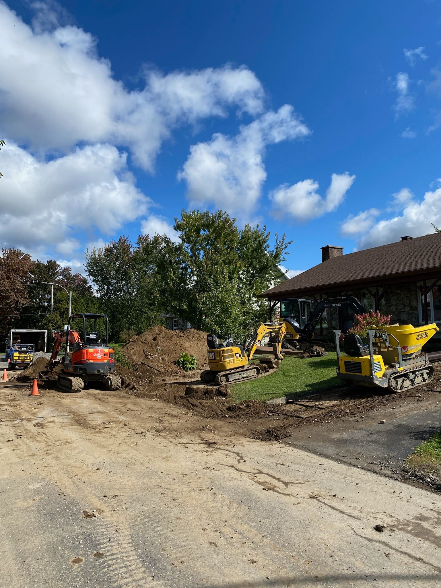 Un groupe de véhicules de construction est garé devant une maison.