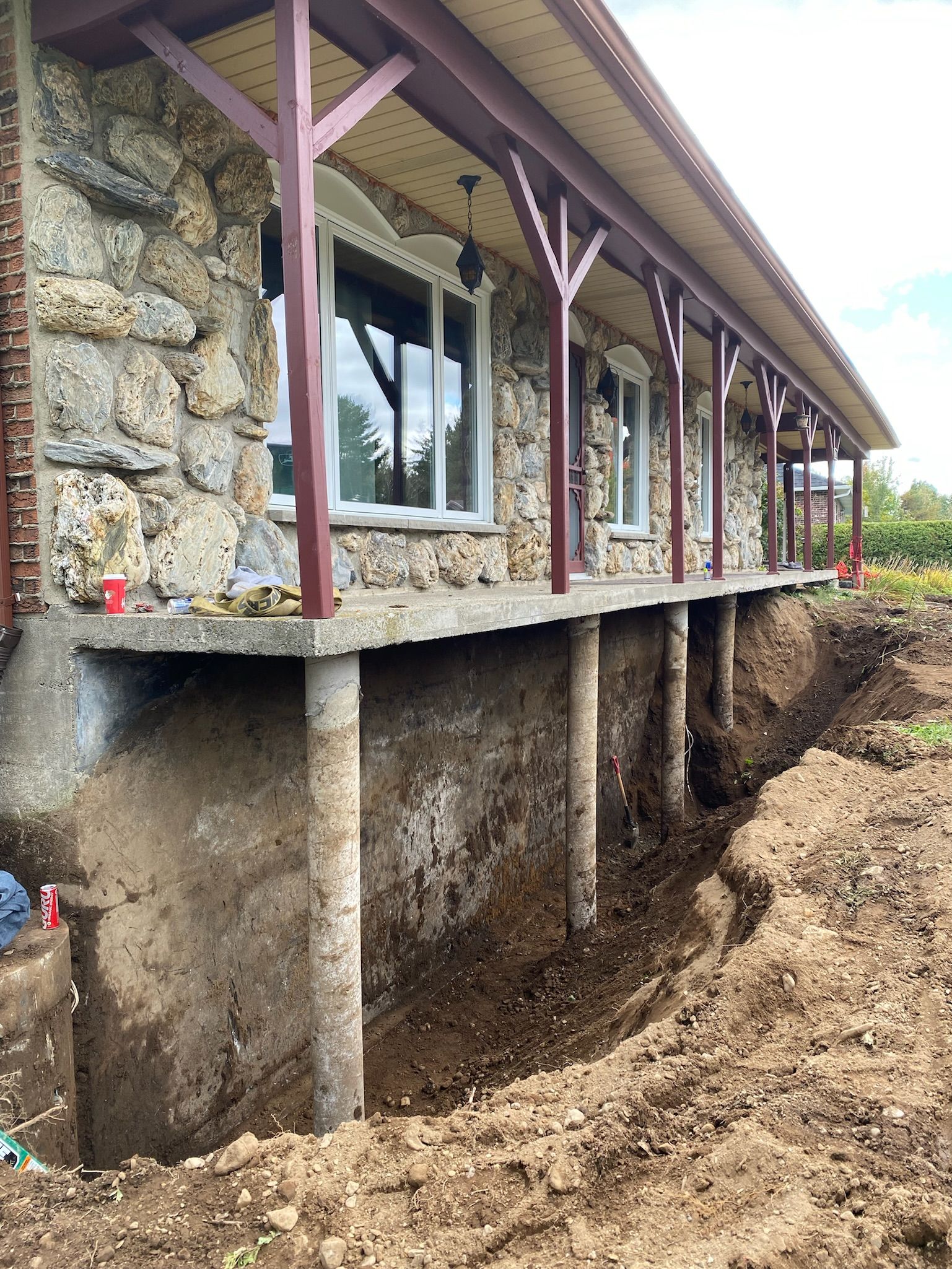 Une maison en pierre avec un porche et un trou dans le sol devant.