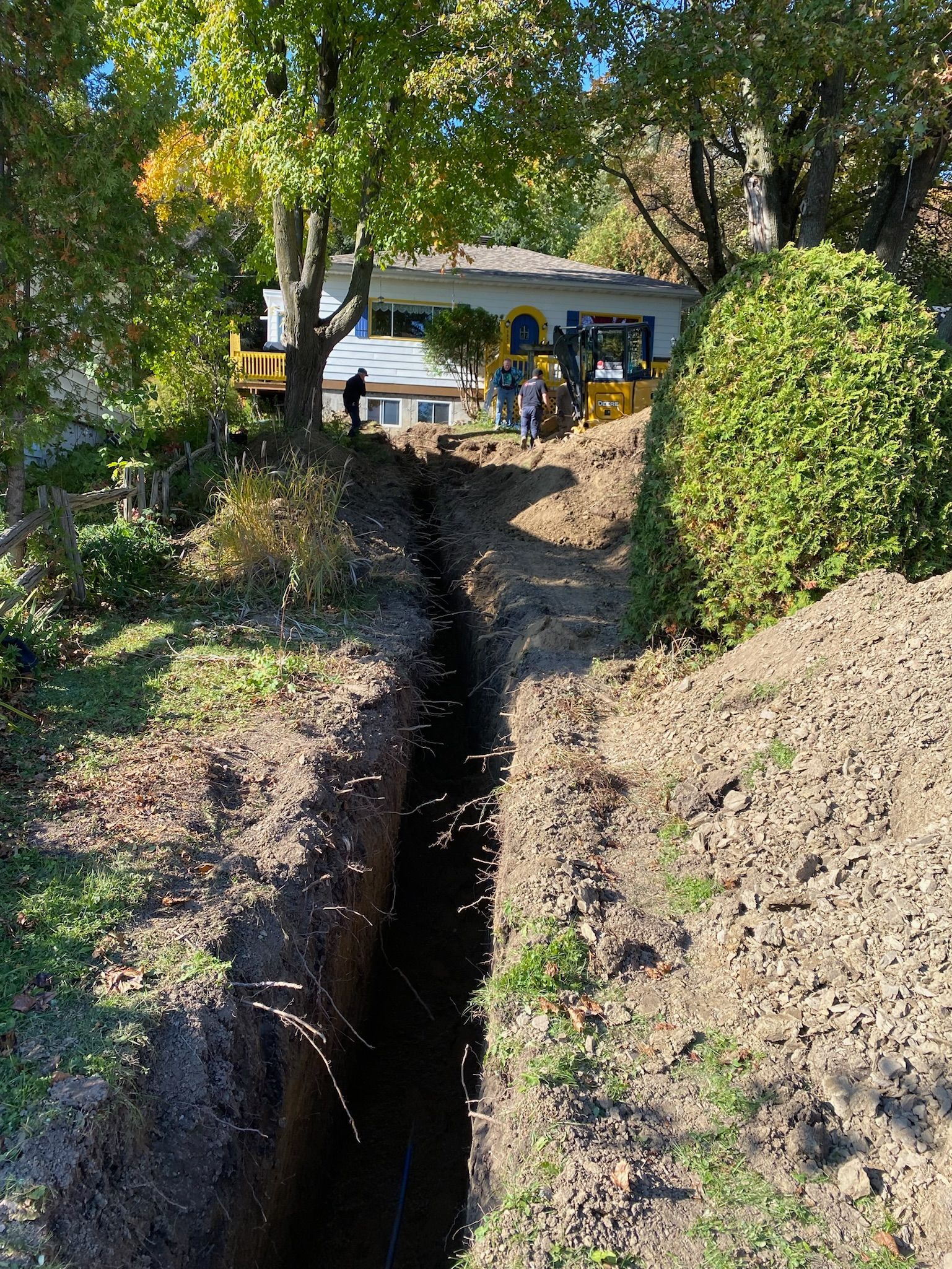Une grande tranchée est creusée dans la terre devant une maison.