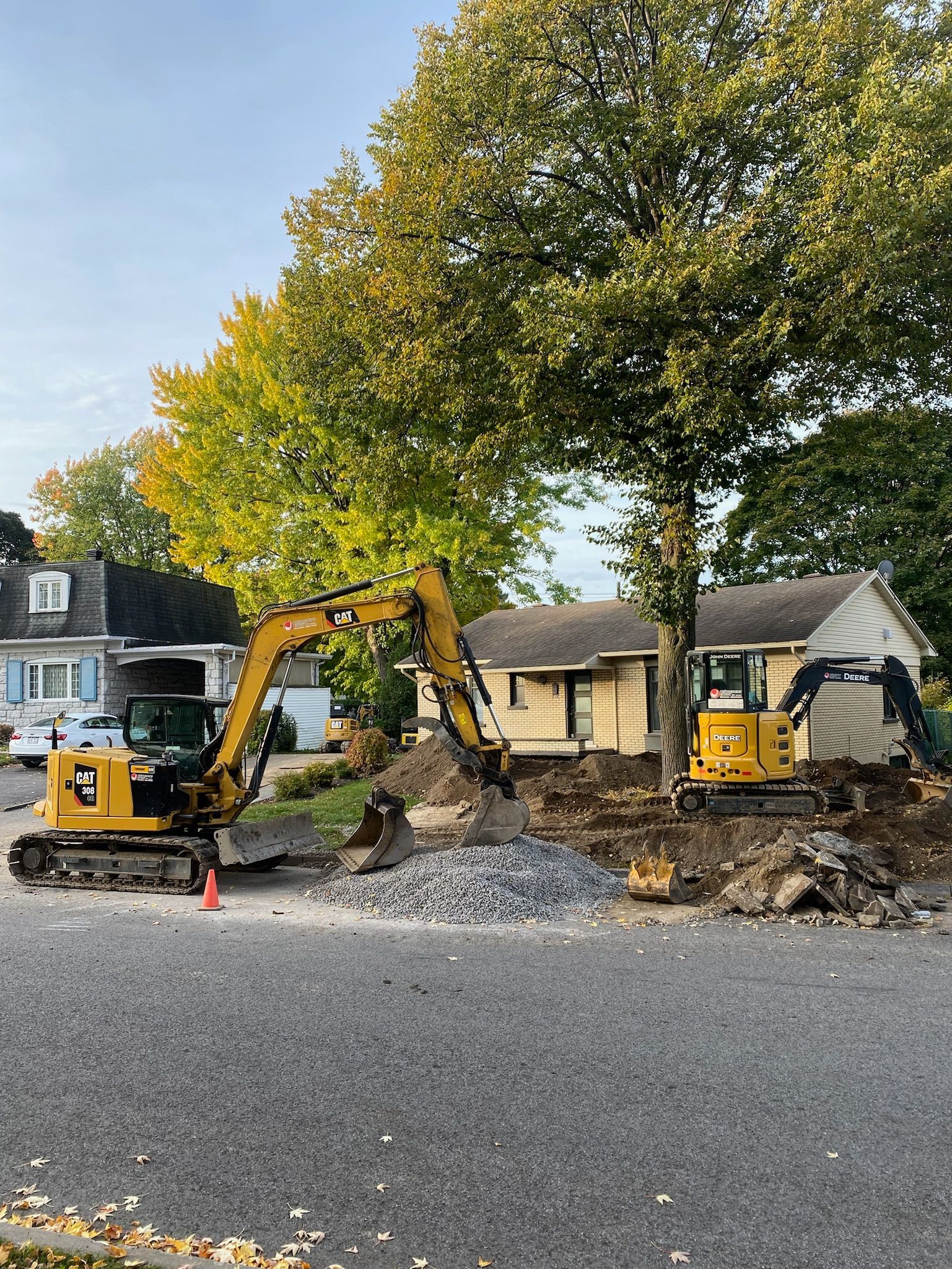 Une excavatrice jaune creuse un trou devant une maison.