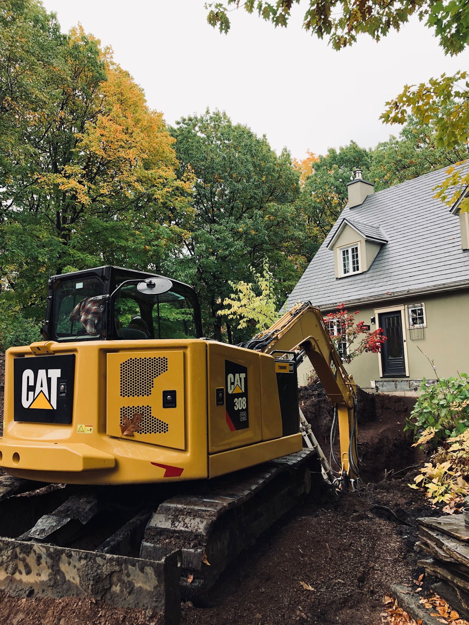 Une excavatrice à chat creuse devant une maison