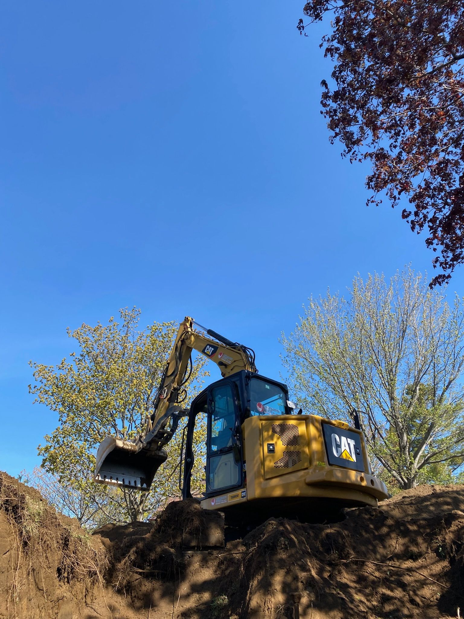 Une excavatrice jaune est assise sur un tas de terre.