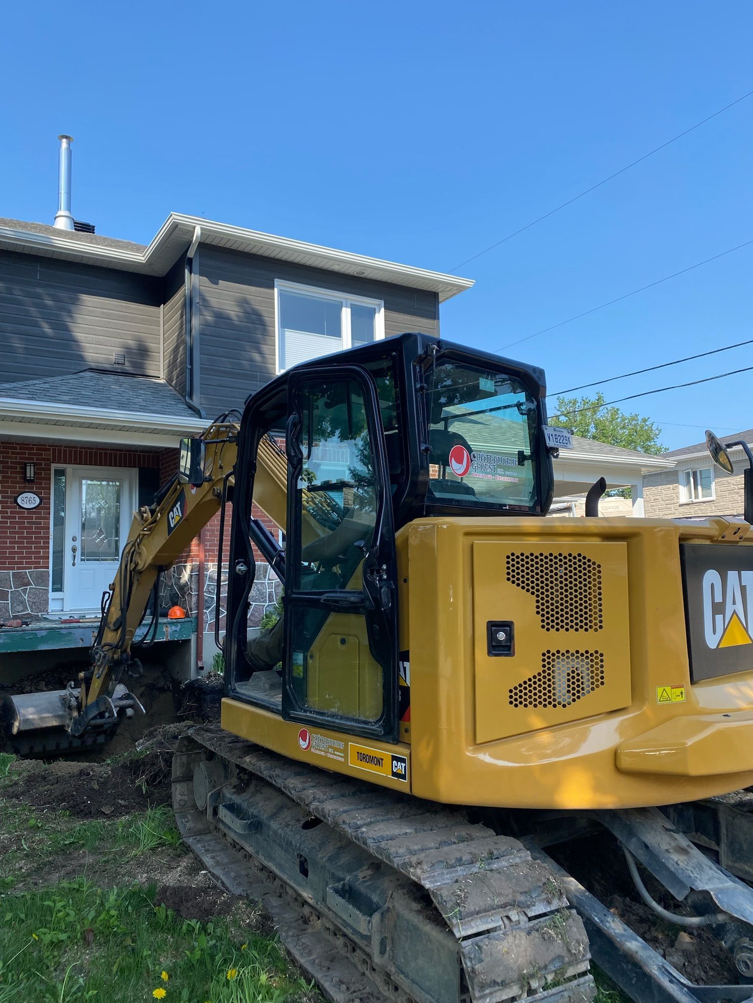 Une excavatrice jaune est garée devant une maison.