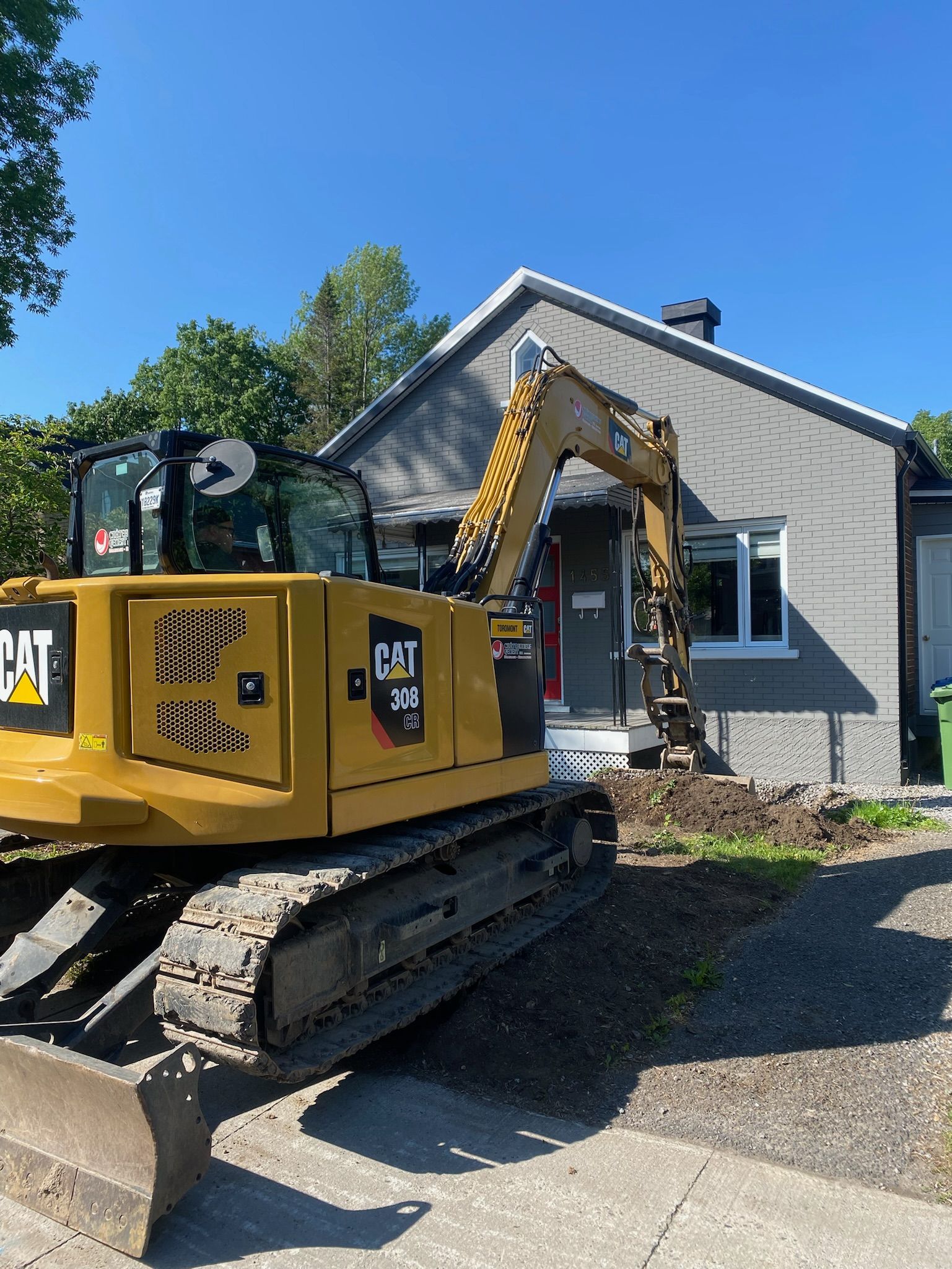 Une excavatrice jaune est garée devant une maison.