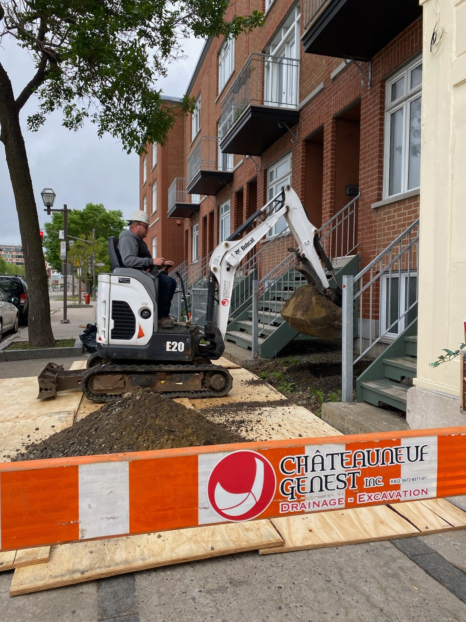 Un homme conduit un bulldozer sur un trottoir devant un bâtiment.