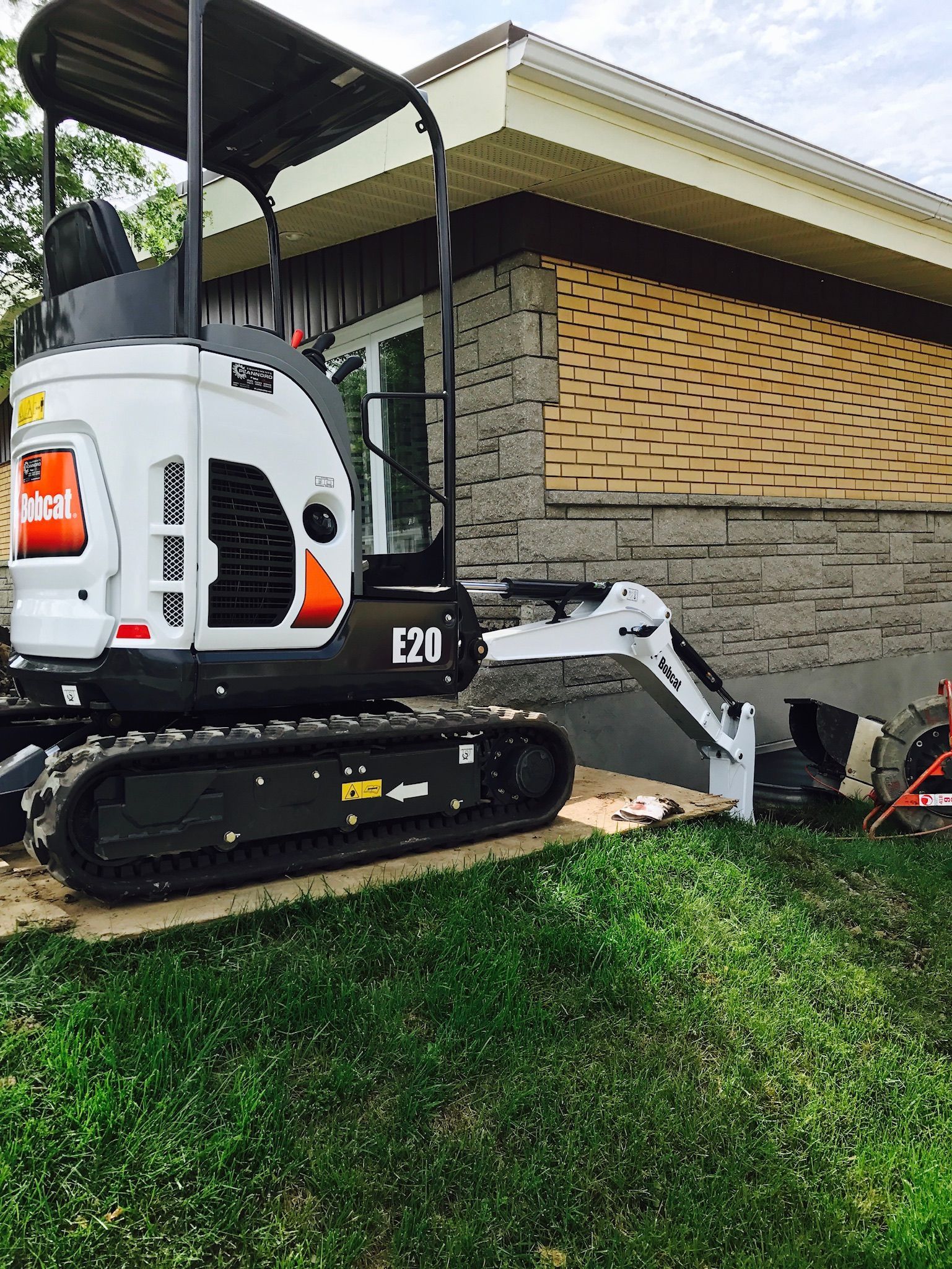 Une petite excavatrice est garée devant une maison.