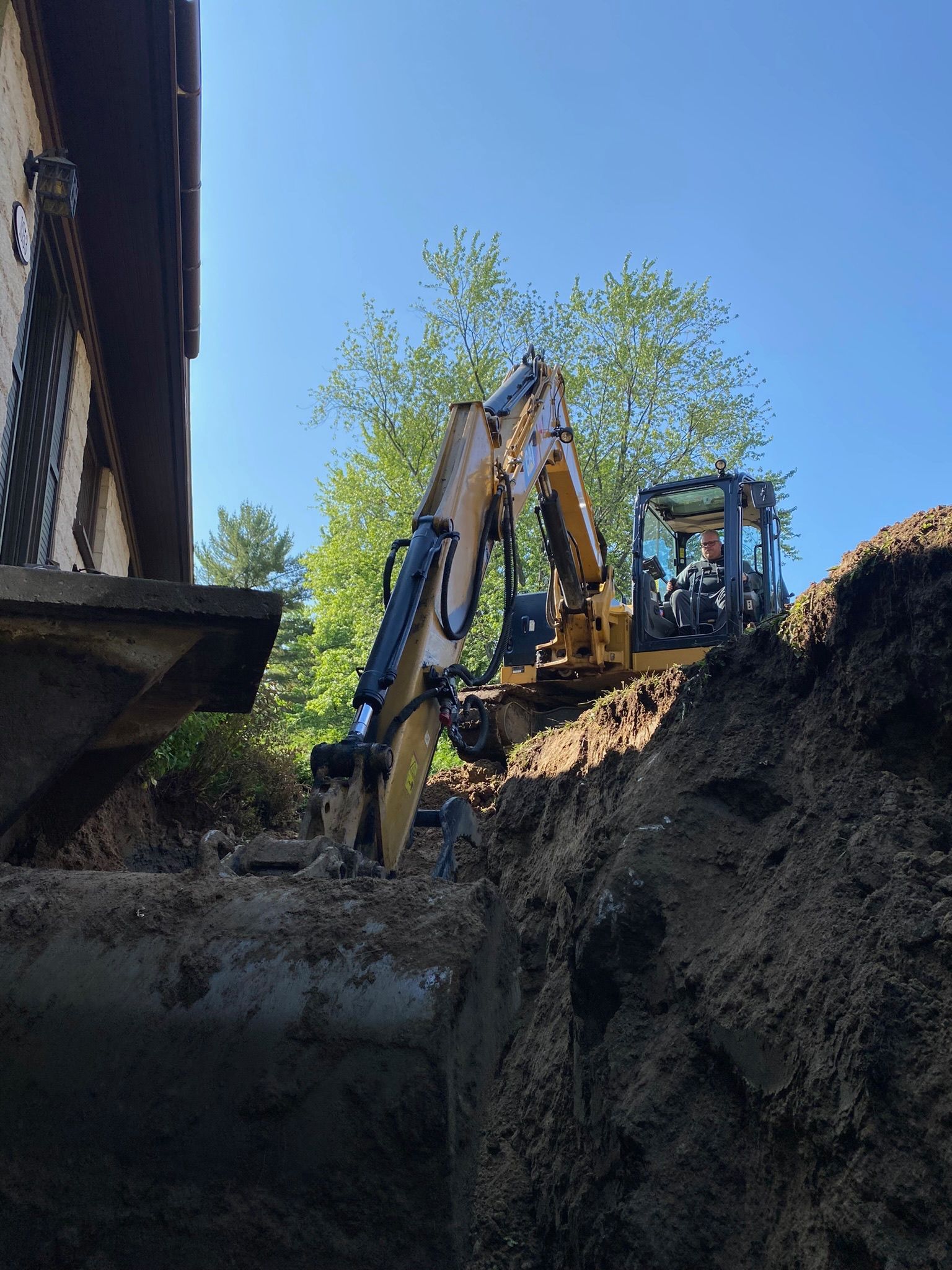 Un bulldozer creuse un trou dans le sol devant un bâtiment.