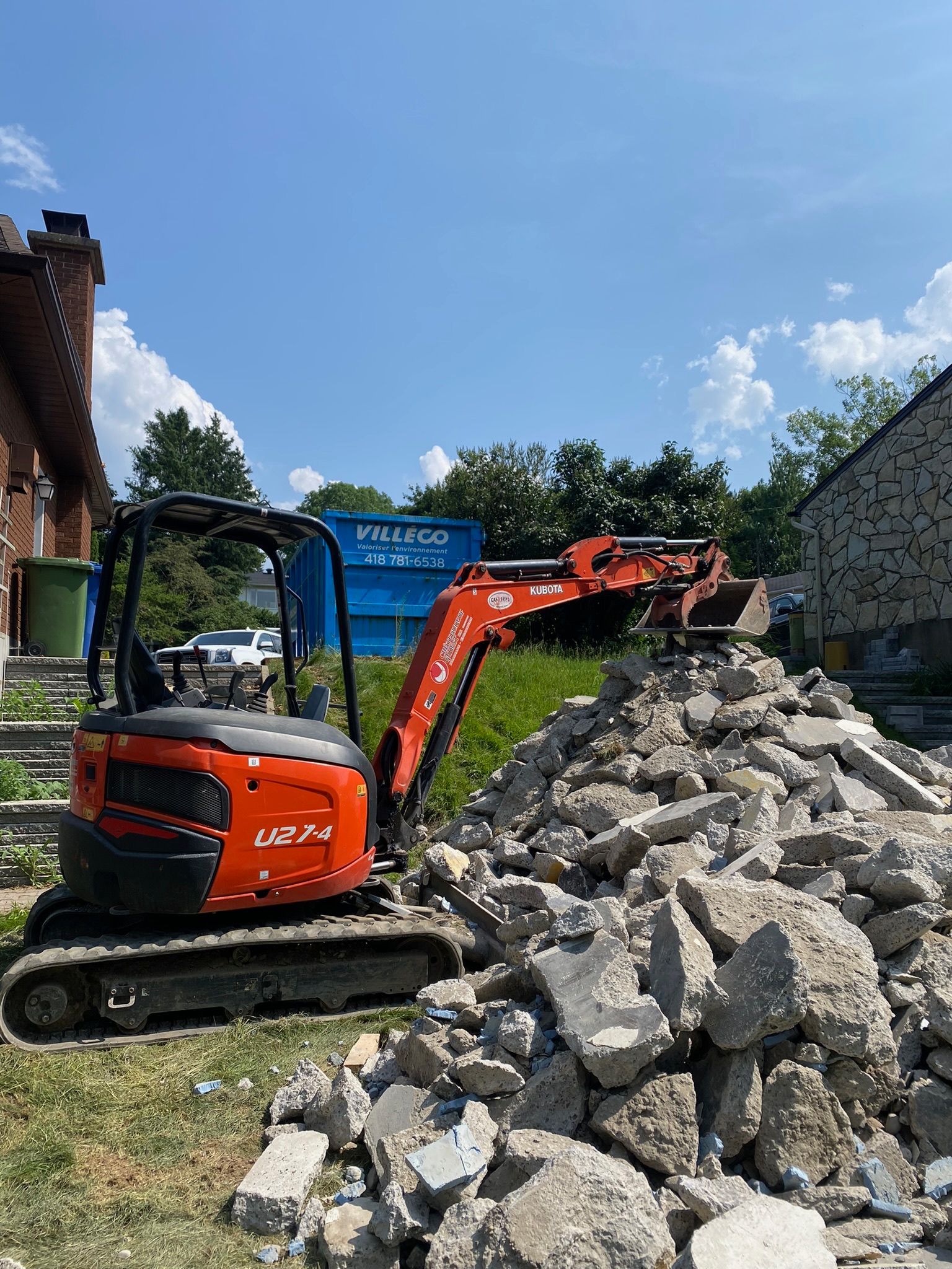 Une petite excavatrice est assise au sommet d'un tas de rochers.