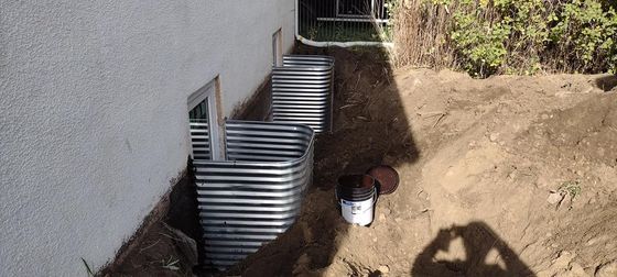 Metal window well installations, soil, wall.