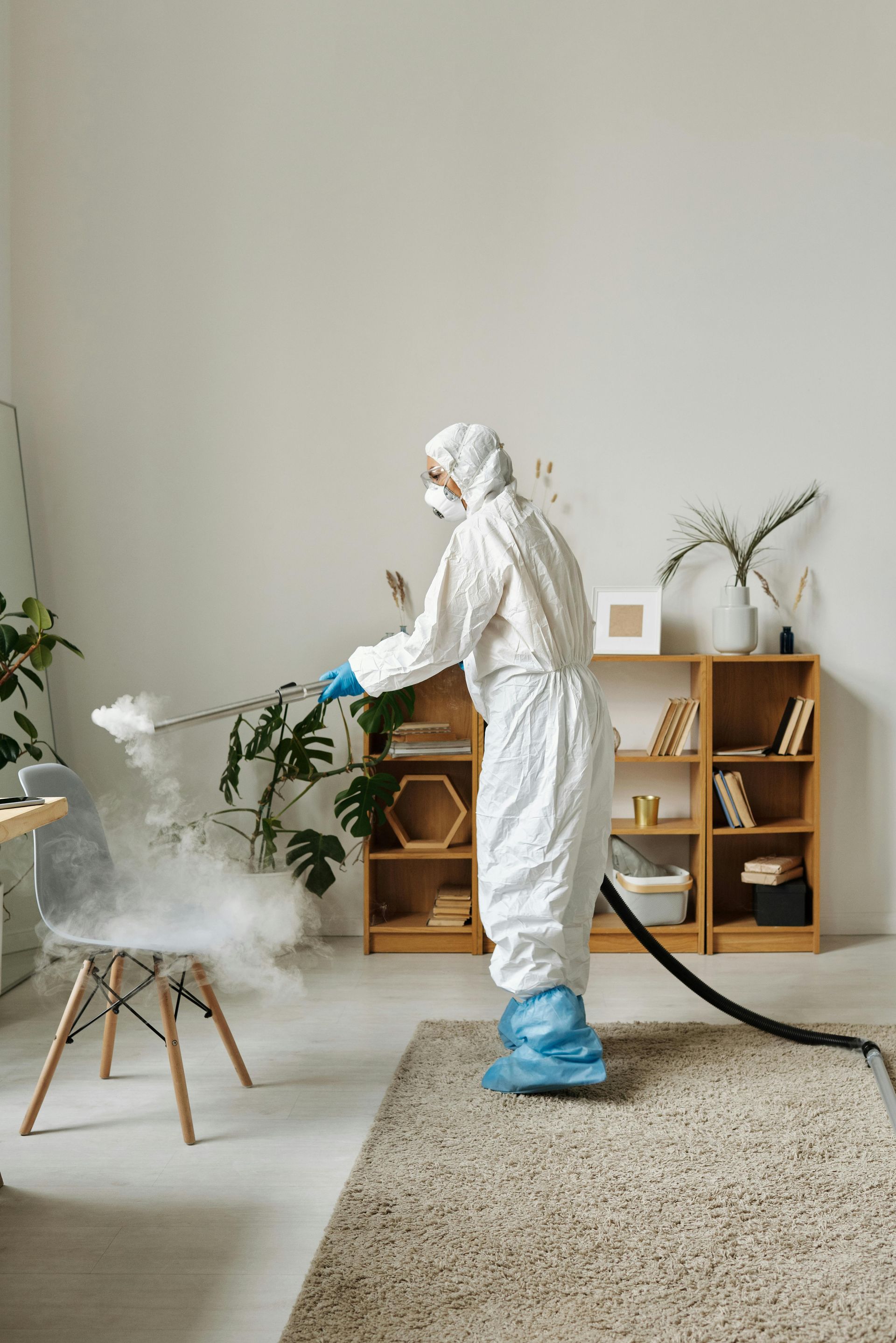Person in hazmat suit disinfecting a room with a fogging machine.