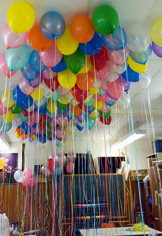 Colorful balloons fill a ceiling, with streamers hanging down.