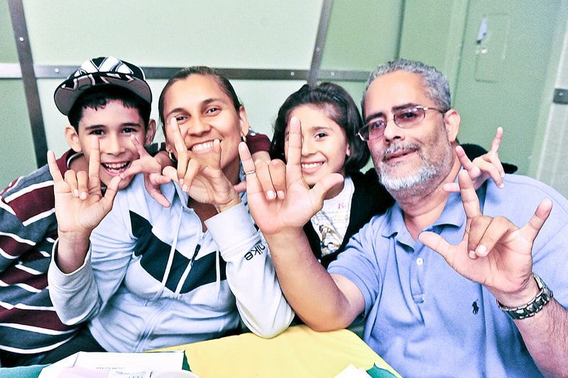 Family, smiling and using ASL sign for 
