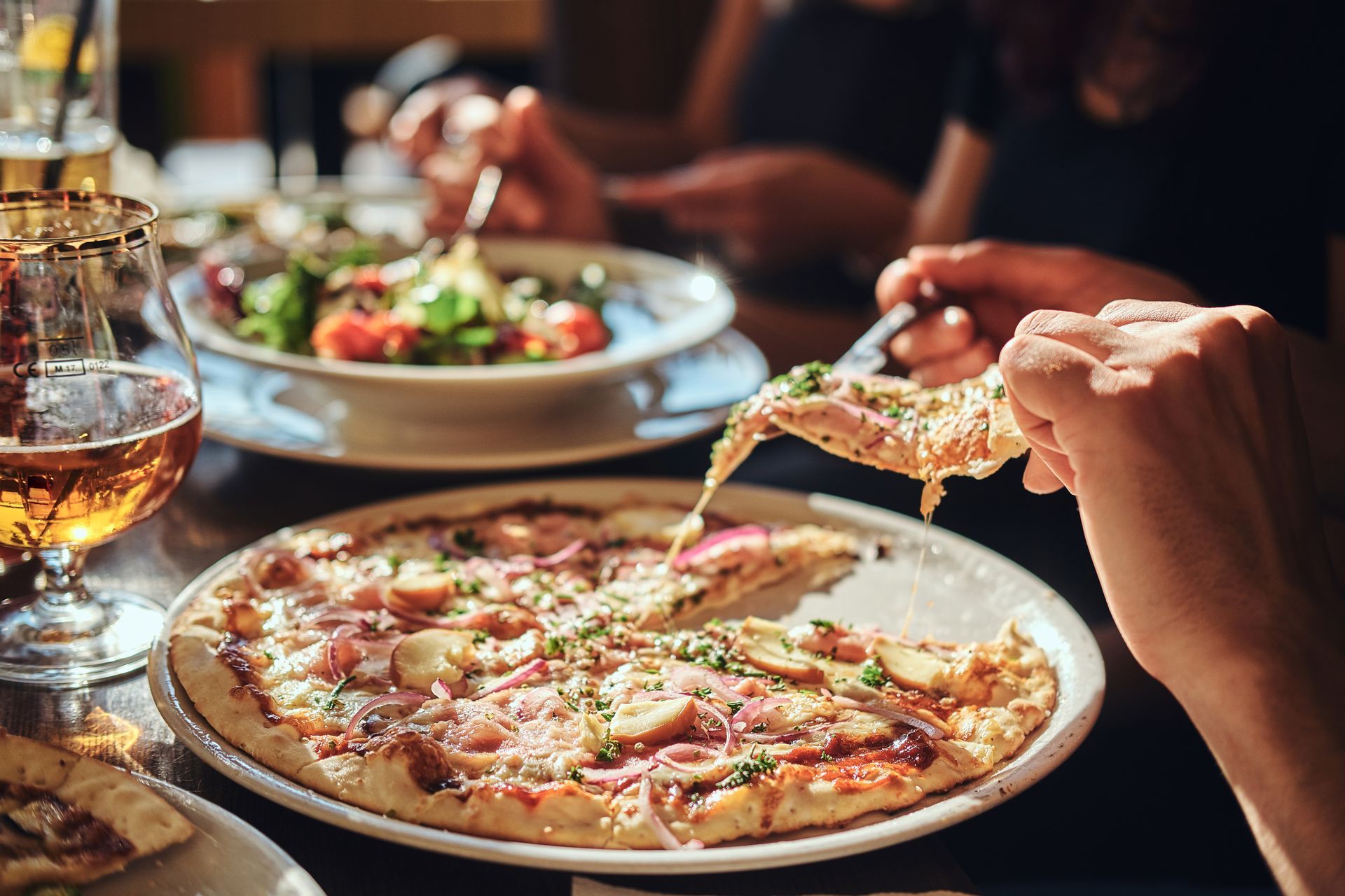 Close-up of a thin-crust pizza being served at a cozy Italian restaurant table.