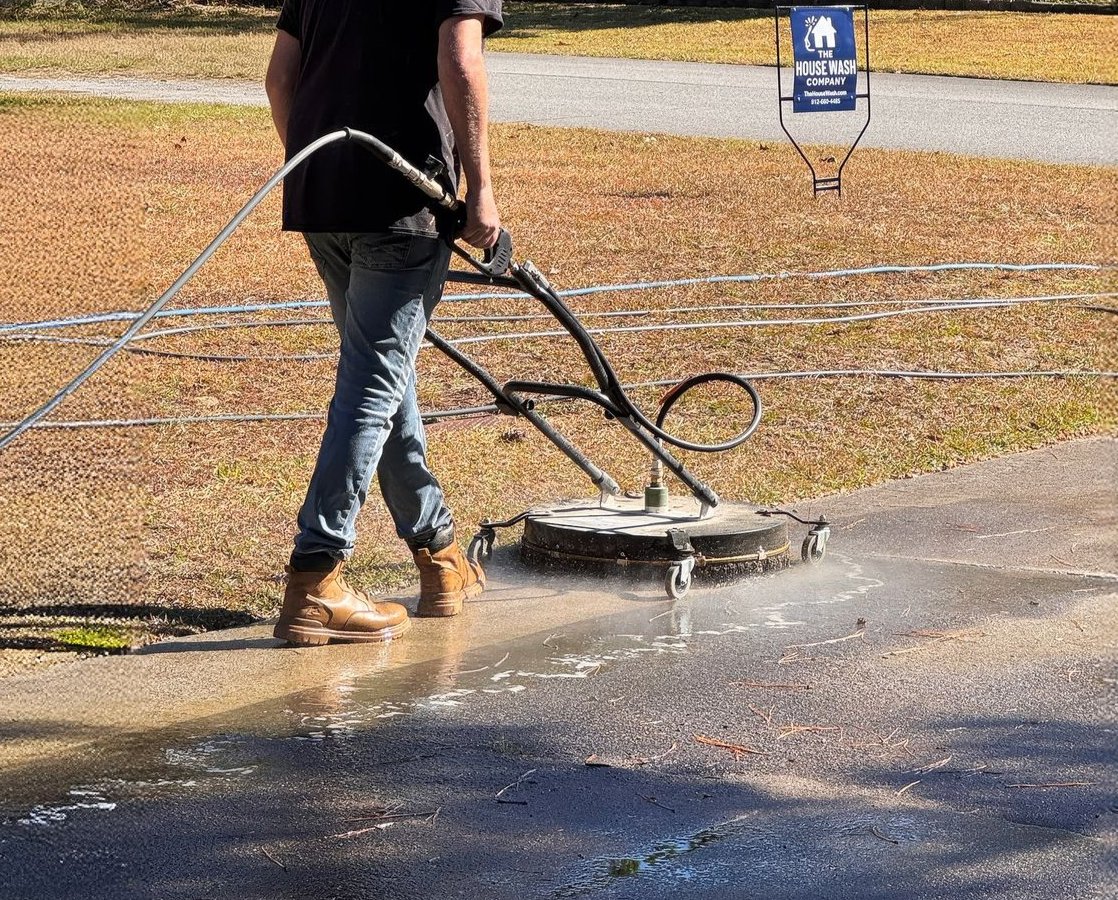 Person power washing a paved walkway outdoors.