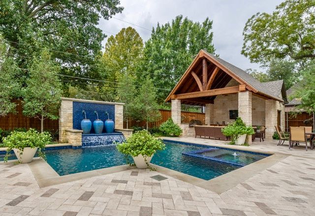 Rectangular backyard pool with stone surround; two red chairs are near the hot tub.