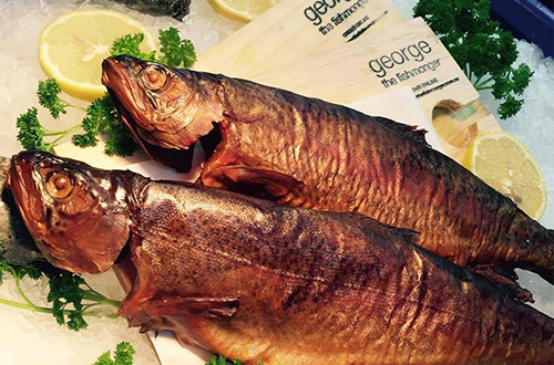 Two smoked fish are sitting on ice with lemons and parsley