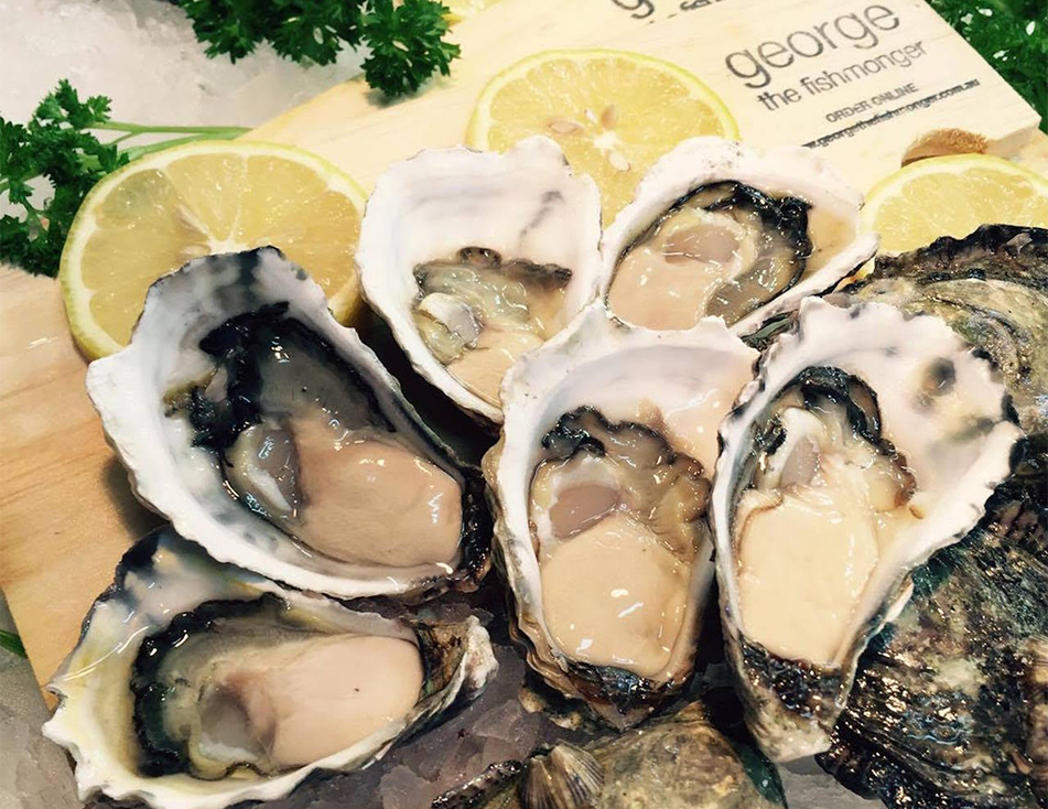 A bunch of oysters on a cutting board with lemons and parsley