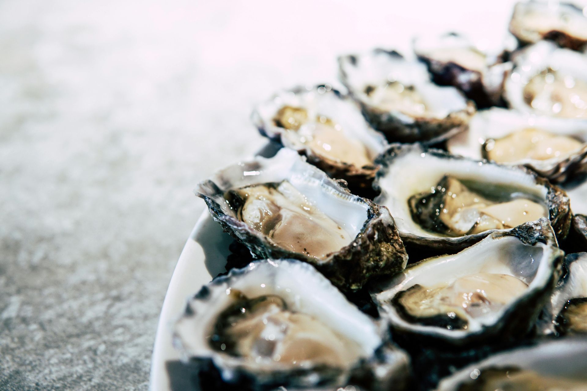 A plate of oysters is sitting on a table.