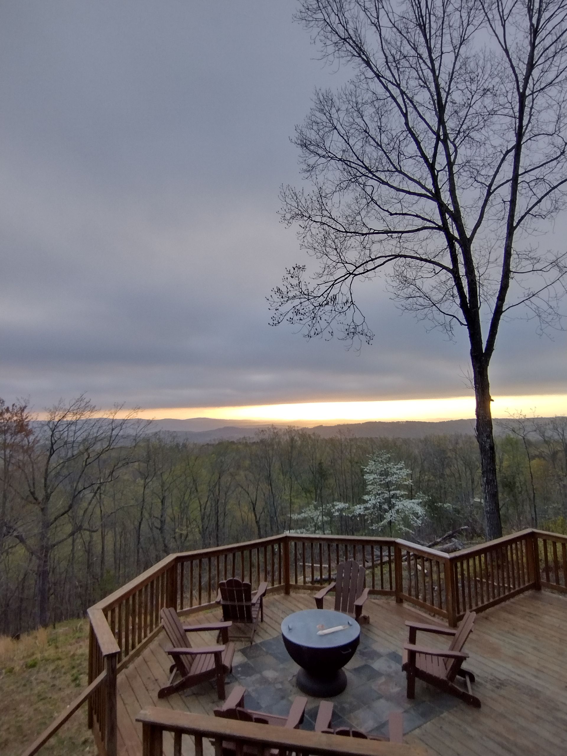 The sun is setting over a forest with mountains in the background.