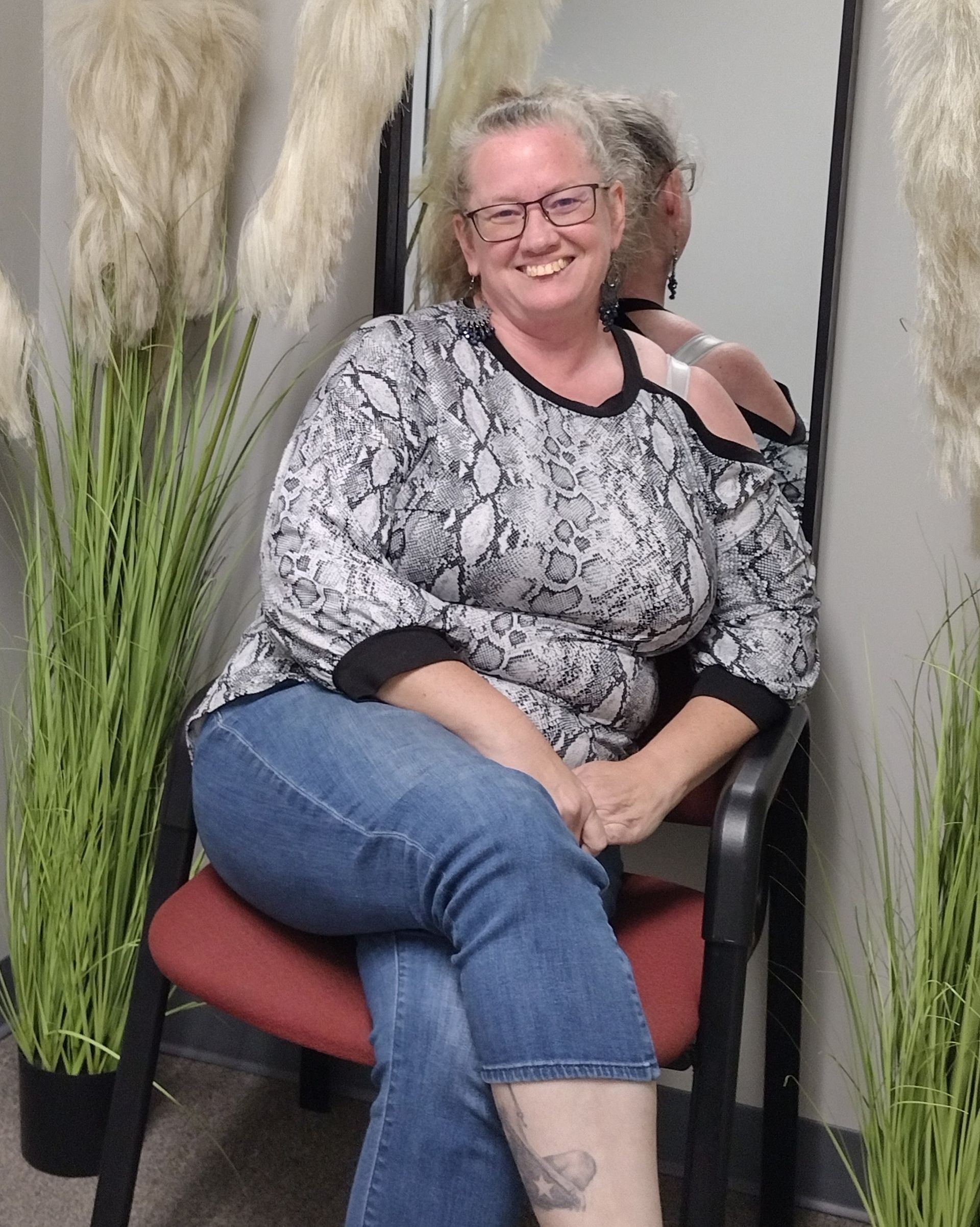 A woman with curly hair and glasses is smiling for the camera.
