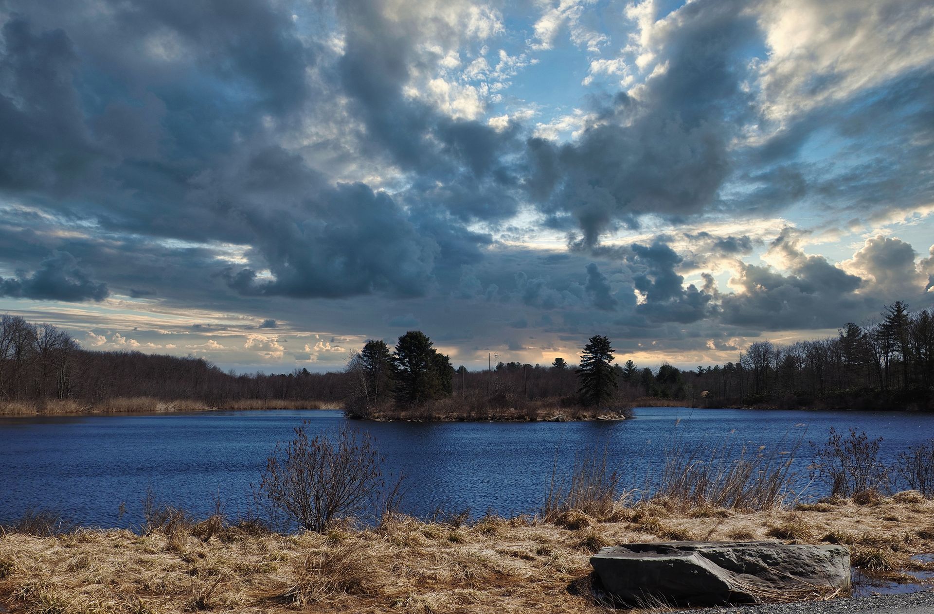 A lake with a cloudy sky and trees in the background