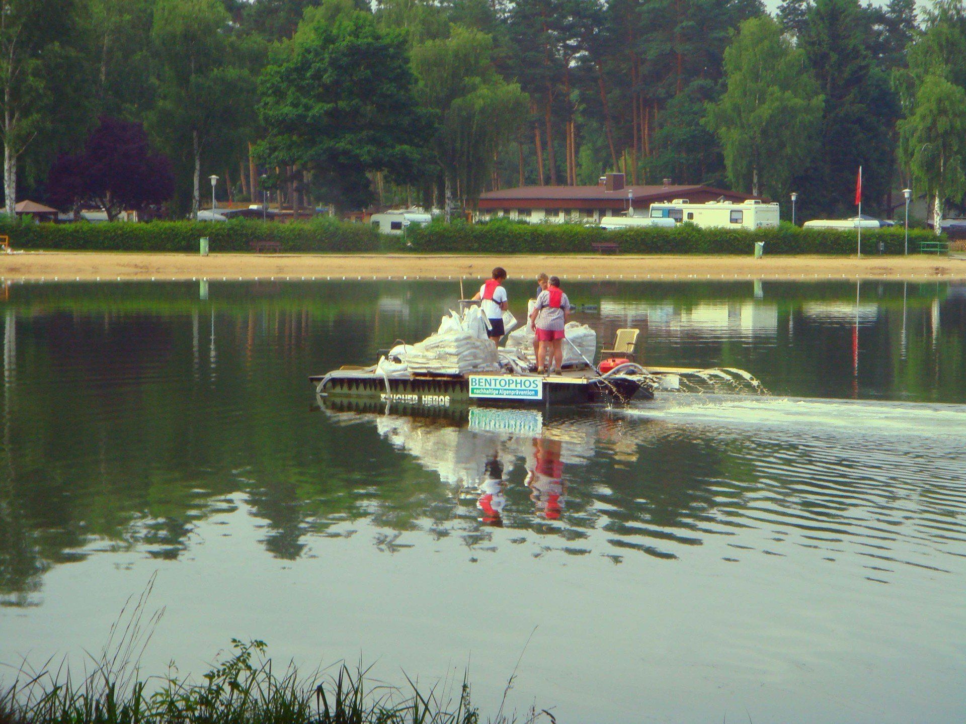A group of people are standing on a raft in the middle of a lake.