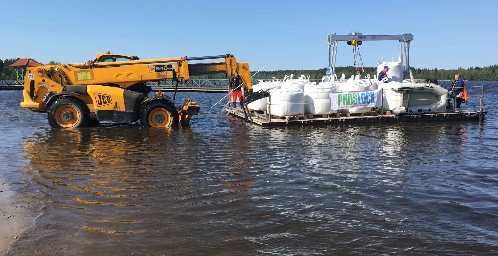 A yellow truck is towing a boat in the water.