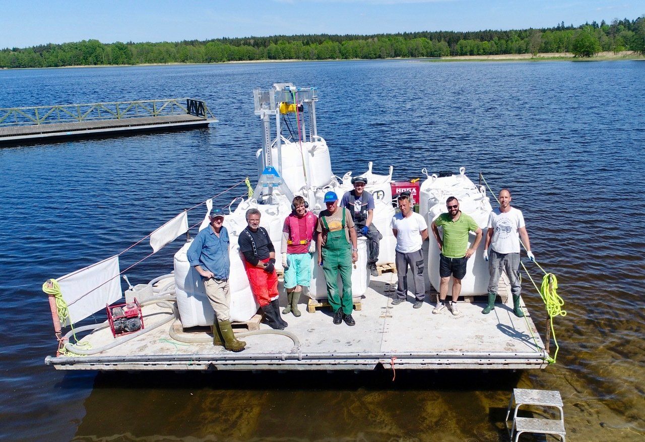A group of people are standing on a boat in the water.
