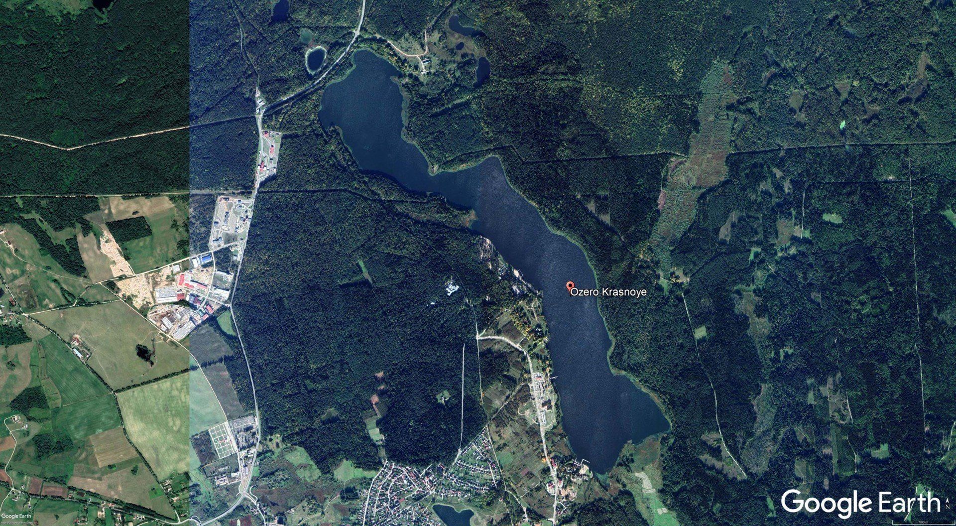 An aerial view of a lake surrounded by trees and fields.