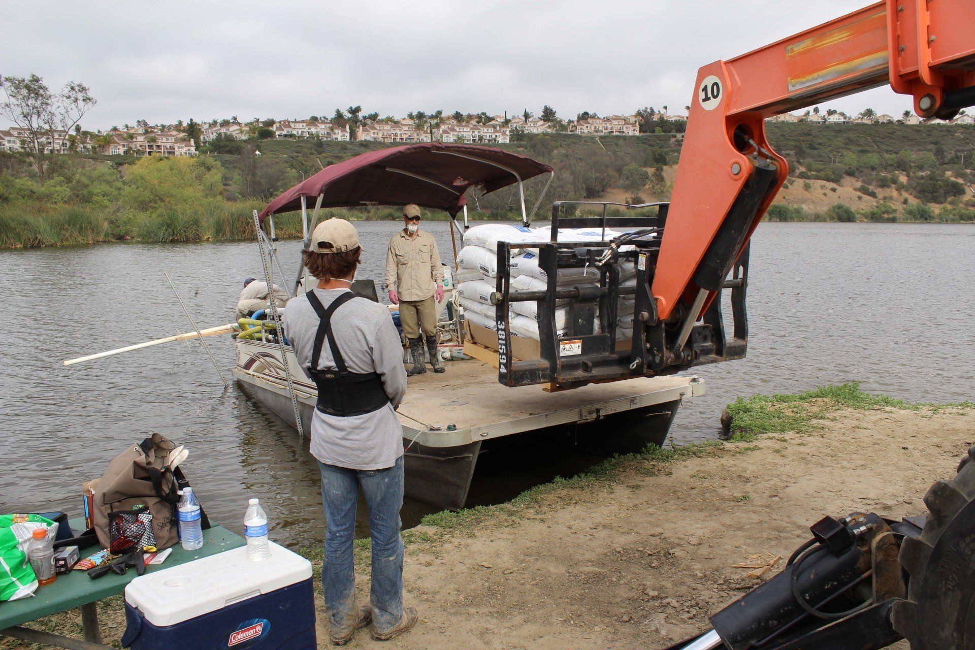 A man is standing next to a boat that is being lifted by a crane